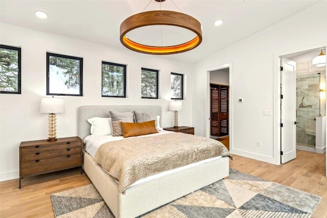 bedroom featuring recessed lighting, vaulted ceiling, ensuite bath, light wood-type flooring, and baseboards