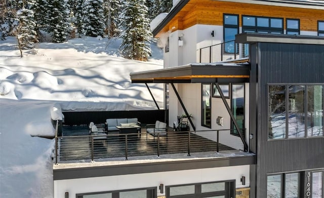 snow covered property featuring a balcony and outdoor lounge area