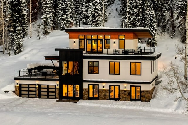 exterior space with a balcony, stone siding, a garage, and stucco siding