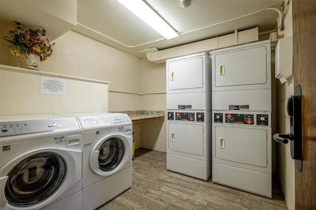 laundry room with light hardwood / wood-style floors, stacked washing maching and dryer, and washing machine and clothes dryer