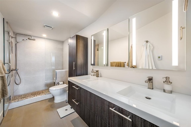 bathroom with tile patterned floors, toilet, vanity, and a tile shower