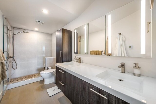 bathroom featuring tiled shower, toilet, tile patterned floors, and vanity