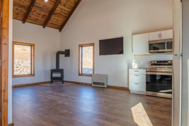 kitchen featuring a wood stove, white cabinetry, high vaulted ceiling, wood ceiling, and appliances with stainless steel finishes