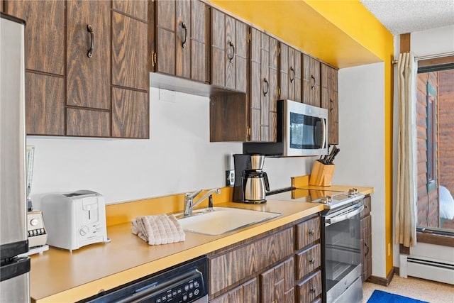 kitchen featuring sink, a baseboard heating unit, a textured ceiling, and appliances with stainless steel finishes