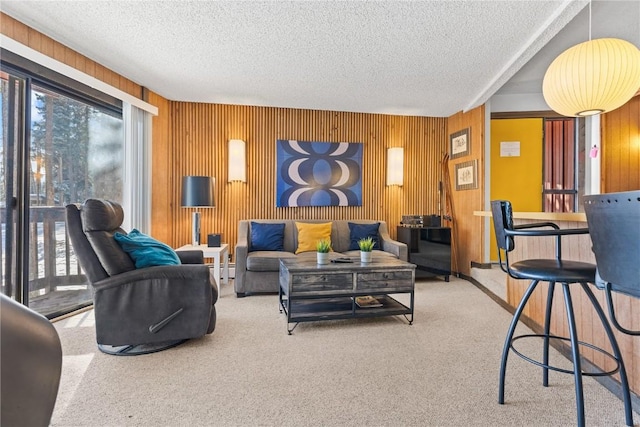 living room with a textured ceiling, wood walls, and carpet flooring