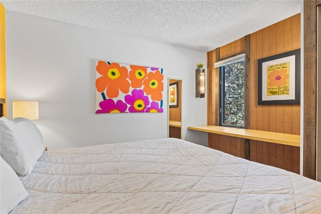 bedroom featuring a textured ceiling and wood walls