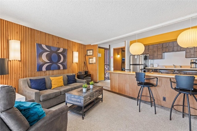 living room featuring wooden walls, a textured ceiling, and light colored carpet