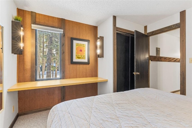 bedroom with a textured ceiling, light colored carpet, and wooden walls