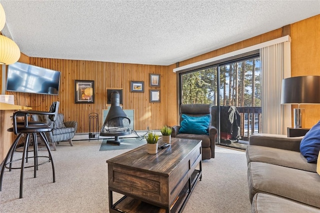 living room featuring a textured ceiling, wood walls, light carpet, and a wood stove