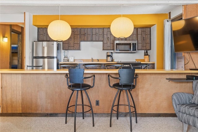 kitchen with stainless steel appliances, a breakfast bar area, hanging light fixtures, and kitchen peninsula