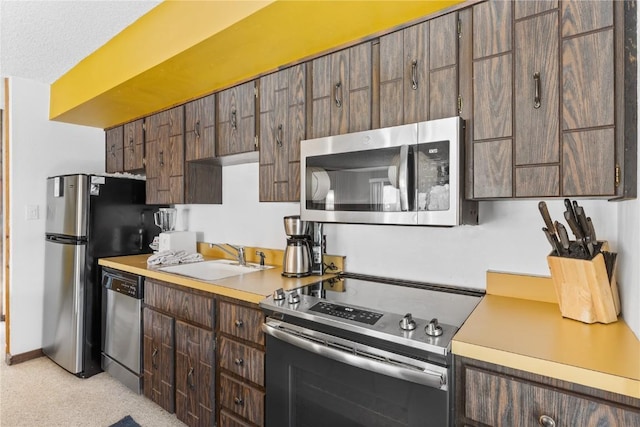 kitchen with a textured ceiling, appliances with stainless steel finishes, and sink