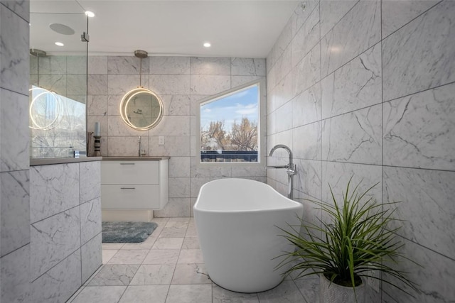 bathroom with vanity, a tub to relax in, and tile walls