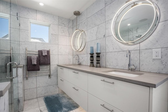 bathroom featuring vanity, a healthy amount of sunlight, a shower with door, and tile walls