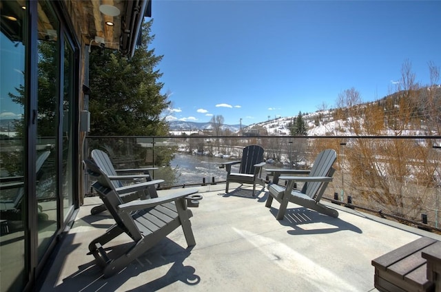 snow covered patio featuring a mountain view and a balcony