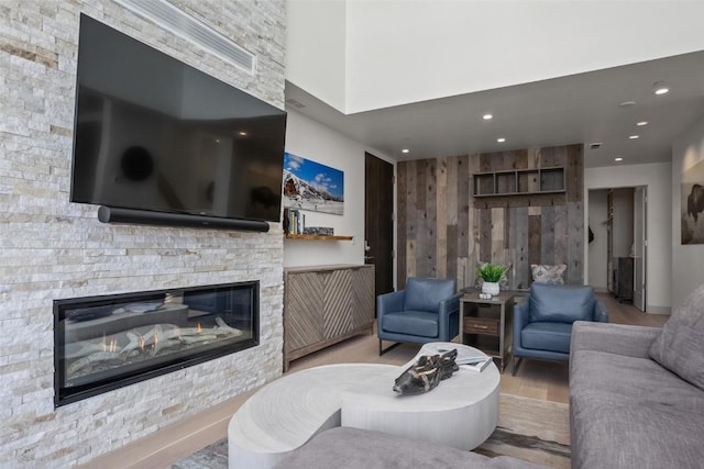 living room featuring a fireplace, light hardwood / wood-style flooring, and wood walls