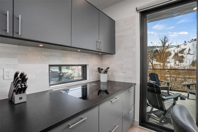 kitchen featuring backsplash, gray cabinetry, a mountain view, and stovetop