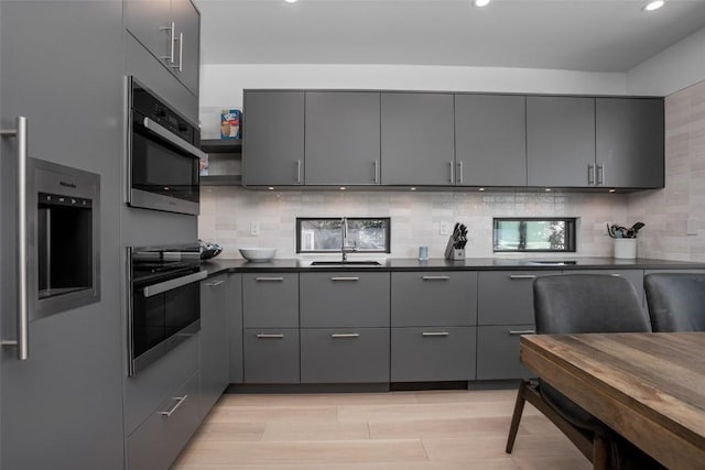 kitchen with wall oven, oven, gray cabinets, and sink