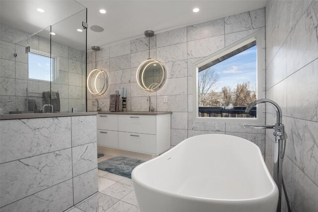 bathroom featuring separate shower and tub, vanity, and tile walls