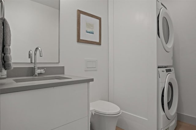 bathroom with vanity, toilet, and stacked washer / dryer