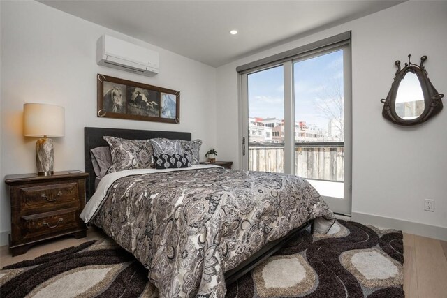 bedroom with hardwood / wood-style floors and an AC wall unit