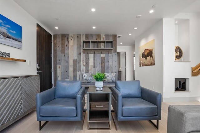 living area featuring light wood-type flooring and wooden walls