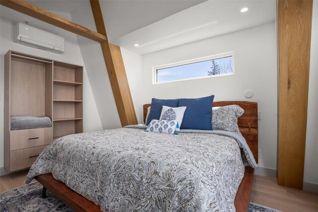 bedroom featuring hardwood / wood-style flooring and a wall unit AC