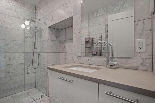 bathroom with vanity, a tile shower, and tile walls