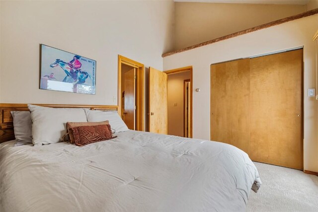 carpeted bedroom with a closet and high vaulted ceiling