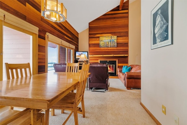 carpeted dining area with high vaulted ceiling and a chandelier