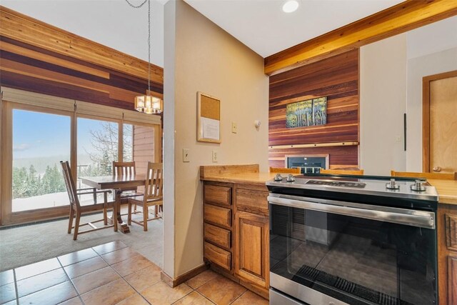 kitchen with wooden walls, pendant lighting, light tile patterned floors, an inviting chandelier, and stainless steel electric range