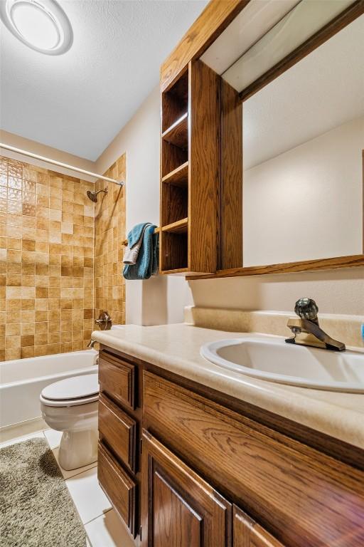 full bathroom featuring tile patterned floors, vanity, toilet, and tiled shower / bath