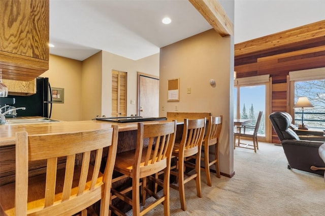 kitchen with beamed ceiling, light colored carpet, and sink