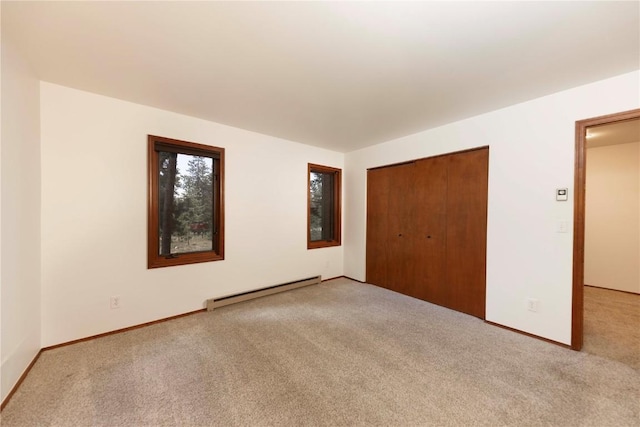 unfurnished bedroom with a closet, baseboard heating, and light colored carpet