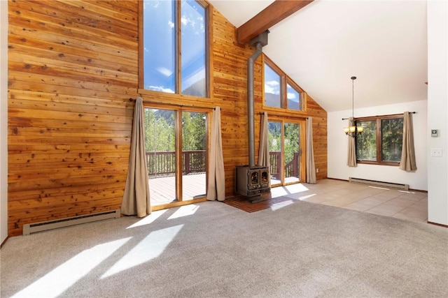 unfurnished living room featuring baseboard heating, a wood stove, high vaulted ceiling, and a healthy amount of sunlight