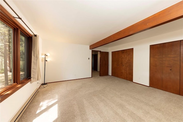 empty room featuring beam ceiling, a healthy amount of sunlight, baseboard heating, and light carpet