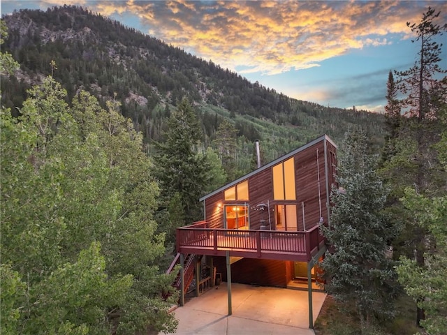 back house at dusk with a deck with mountain view