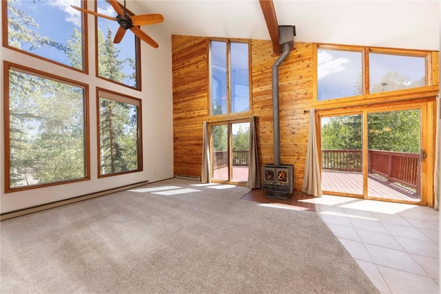 unfurnished living room featuring beam ceiling, light tile patterned floors, a wood stove, and high vaulted ceiling