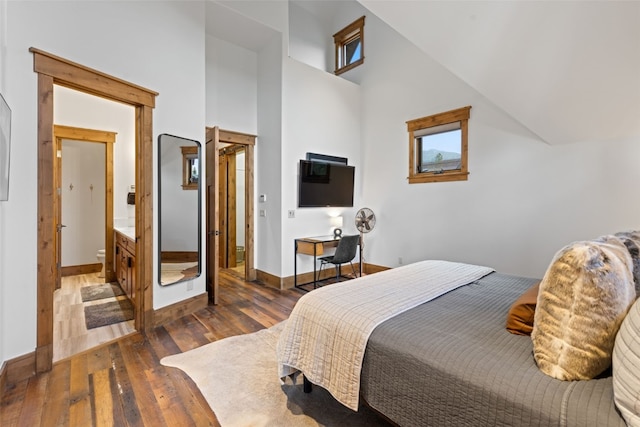 bedroom featuring dark hardwood / wood-style flooring, high vaulted ceiling, and ensuite bath