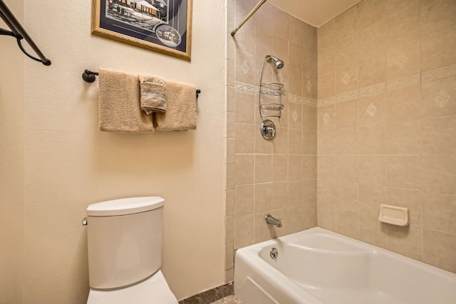 bathroom with toilet and tiled shower / bath