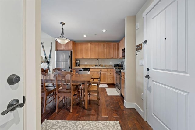 kitchen with sink, hanging light fixtures, light stone counters, dark hardwood / wood-style floors, and appliances with stainless steel finishes