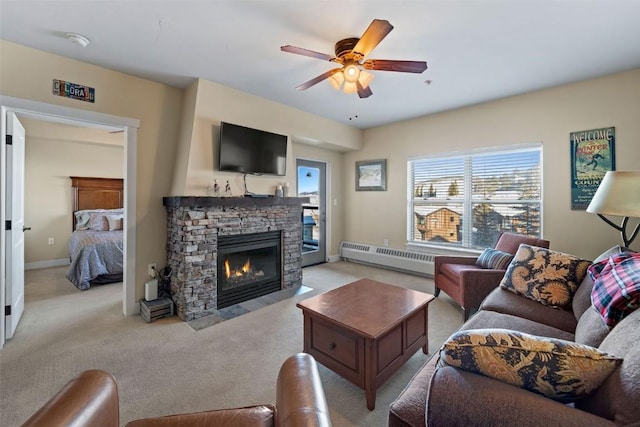 living room featuring light carpet, a baseboard radiator, a stone fireplace, and ceiling fan