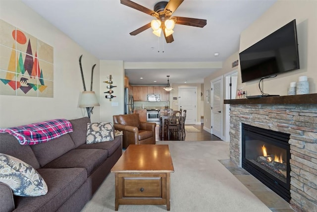 carpeted living room with ceiling fan and a fireplace