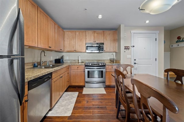 kitchen with appliances with stainless steel finishes, dark hardwood / wood-style flooring, light stone counters, sink, and light brown cabinets