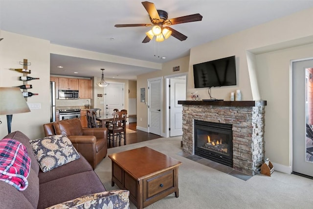 carpeted living room with a fireplace and ceiling fan