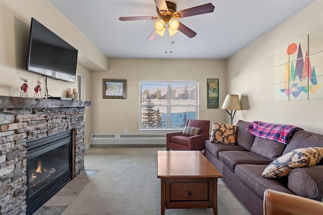 living room featuring radiator, light colored carpet, ceiling fan, a baseboard radiator, and a stone fireplace