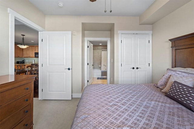 carpeted bedroom with ceiling fan, a closet, and ensuite bath