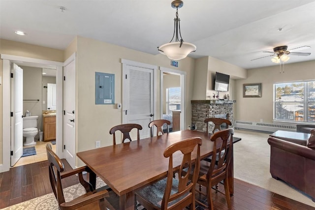 dining area with ceiling fan, baseboard heating, a fireplace, and electric panel