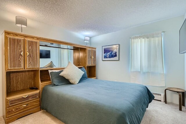 carpeted bedroom featuring a baseboard radiator and a textured ceiling