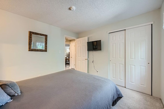 carpeted bedroom featuring a textured ceiling and a closet