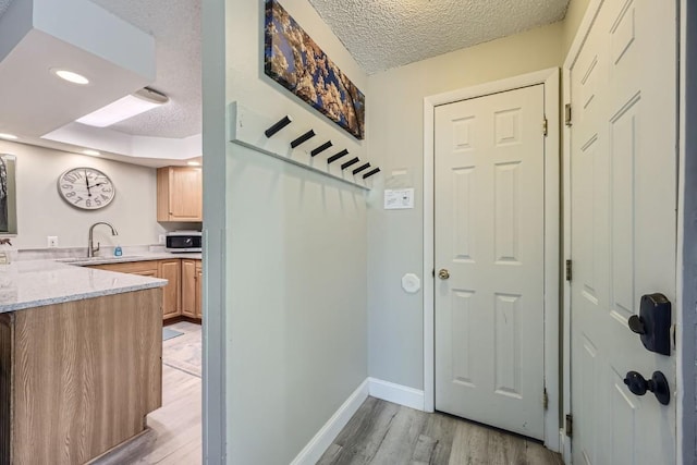 interior space featuring sink, a textured ceiling, and light hardwood / wood-style flooring